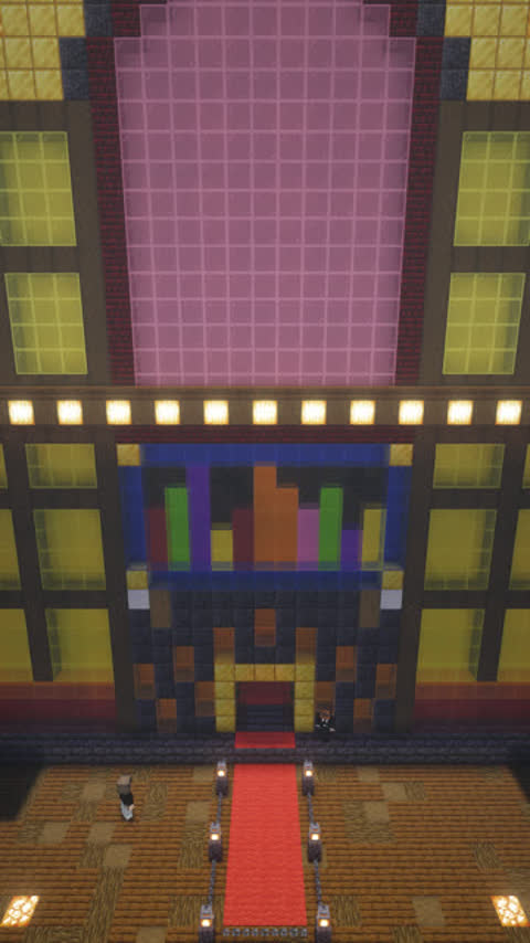 Drone shot rising and pulling back from a giant jukebox building in Minecraft, revealing the full structure and red carpet