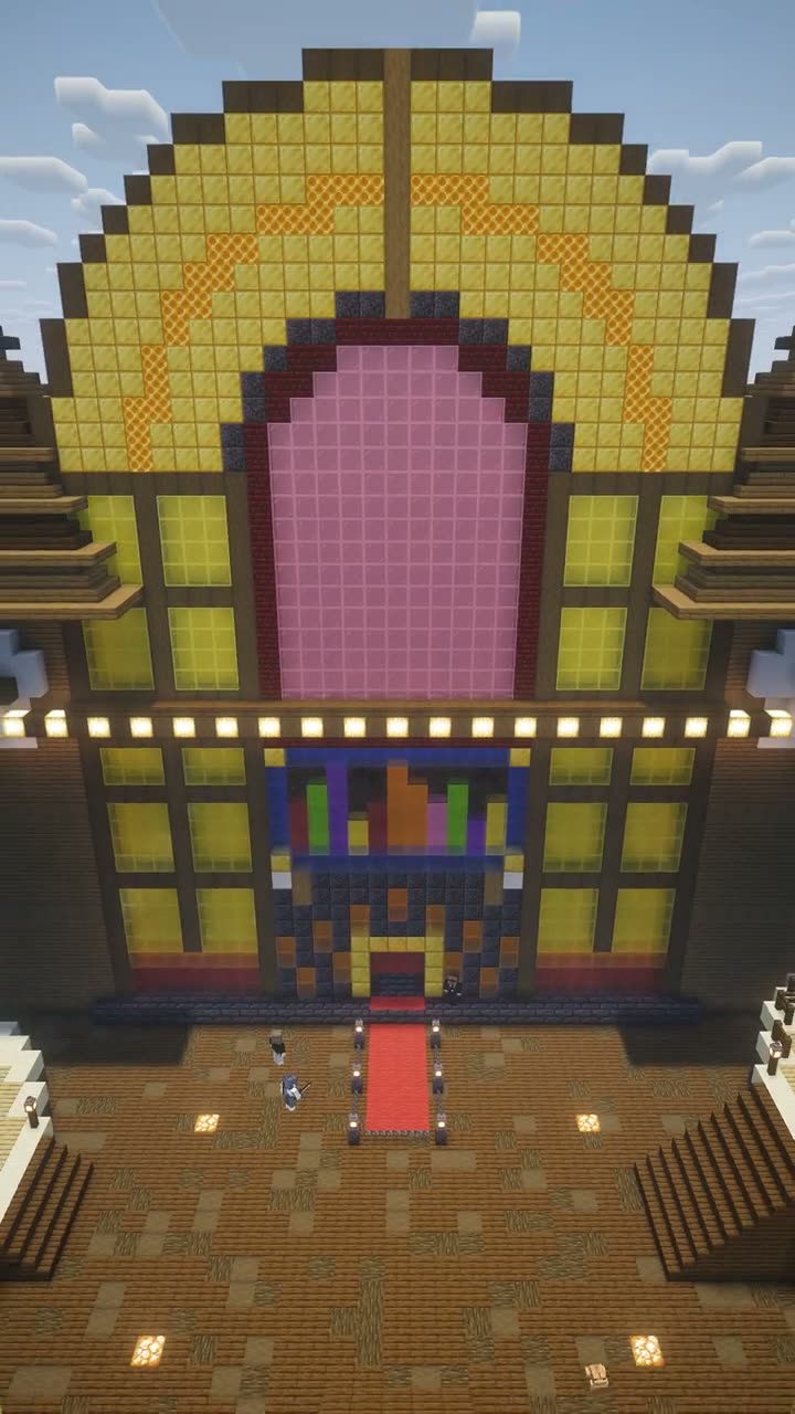 Drone shot pulling back from the front of a giant Minecraft jukebox building, revealing the whole structure and a red carpet